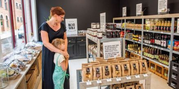 Winkel met streekproducten en een vrouw met kind die de producten bekijken.